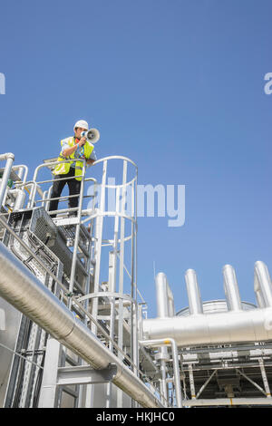 Low angle view of an engineer using a megaphone at geothermal power station, Bavaria, Germany Stock Photo