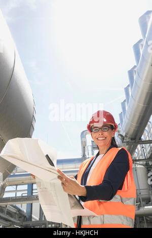 Female engineer smiling with blueprint at geothermal power station, Bavaria, Germany Stock Photo