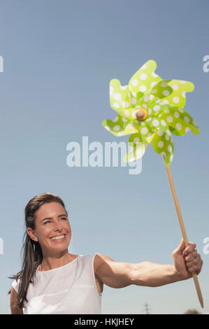 Happy woman with paper windmill at geothermal power station, Bavaria, Germany Stock Photo
