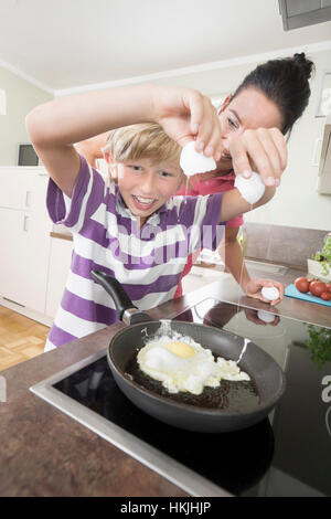 Woman with her son preparing fried eggs in kitchen,Bavaria,Germany Stock Photo
