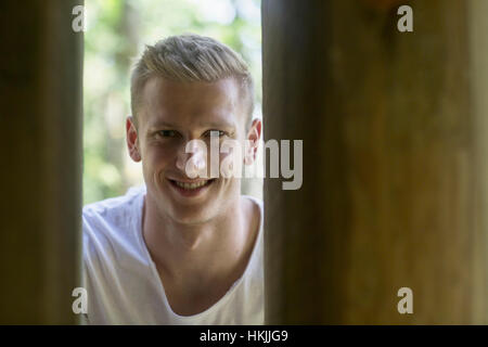 Young man peeking through columns, Freiburg im Breisgau, Baden-Württemberg, Germany Stock Photo
