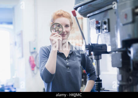 Young female engineer looking through gear in an industrial plant, Freiburg im Breisgau, Baden-Württemberg, Germany
