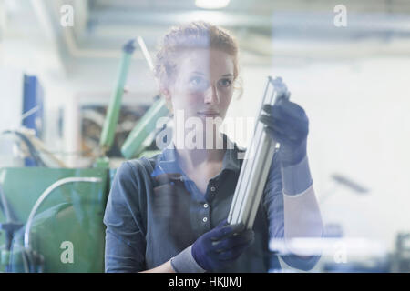 Young female engineer looking at machine part in an industrial plant, Freiburg im Breisgau, Baden-Württemberg, Germany Stock Photo