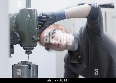 Young female engineer looking at CNC machine in an industrial plant, Freiburg im Breisgau, Baden-Württemberg, Germany Stock Photo