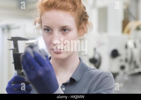 Young female engineer repairing machine part in an industrial plant, Freiburg im Breisgau, Baden-Württemberg, Germany Stock Photo