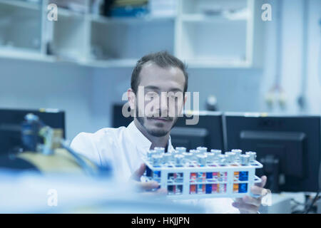 Young male scientist examining test tube in a laboratory, Freiburg Im Breisgau, Baden-Württemberg, Germany Stock Photo