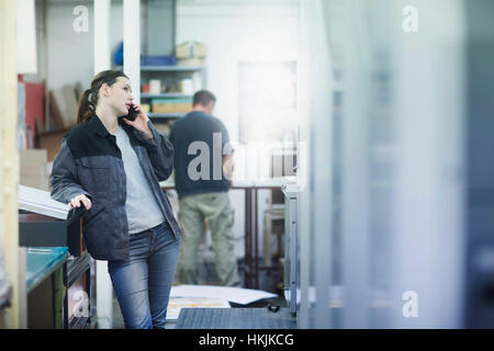 Print worker talking on mobile phone in an industry, Freiburg im Breisgau, Baden-Württemberg, Germany Stock Photo