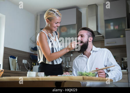 Woman feeding man in the kitchen, Bavaria, Germany Stock Photo
