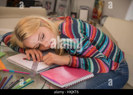 Exhausted student sleeping during doing homework in the living room, Bavaria, Germany Stock Photo