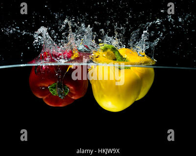 Red and Yellow Paprika Splash in Water Isolated on black Background Stock Photo