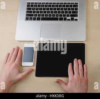 tablet, phone, laptop with hands on wooden table Stock Photo