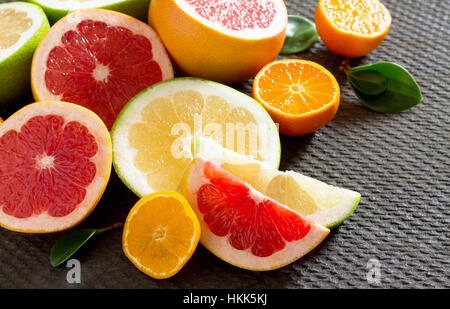 Citrus fruit collection of sliced grapefruits and tangerines on a stone gray background. Fruits background food. Healthy eating and diet. Stock Photo