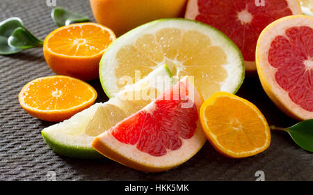 Citrus fruit collection of sliced grapefruits and tangerines on a stone gray background. Fruits background food. Healthy eating and diet. Stock Photo