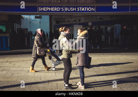 Friends meet and embrace outside Shepherds Bush London Underground station. Stock Photo