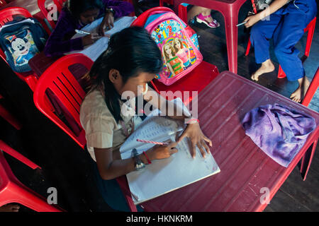 A 10 year old Asian girl is writingl in a notebook at an English language school in Chok Village,  Tboung Khmum Province, Cambodia. Stock Photo