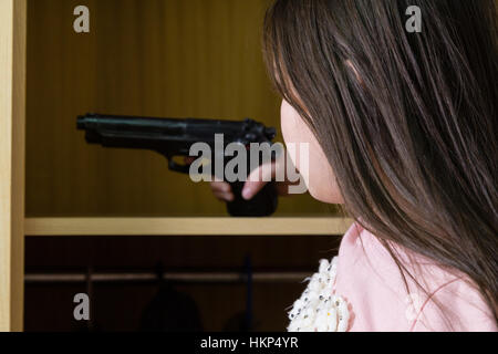 Young child finds pistol in cupboard, gun control concept Stock Photo