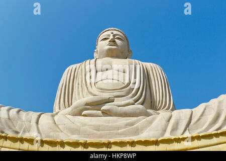 Big statue of white Buddha sitting on lotus India Bodhgaya worm eye view blue sky background Stock Photo