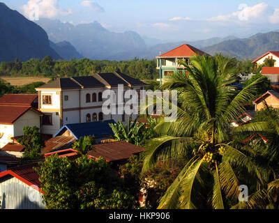 House in mountain village landscape with palm on a foreground and foggy mountains on a background Laos Vang Vieng top view Stock Photo