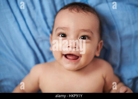 close up of baby boy laying on blue blanket Stock Photo