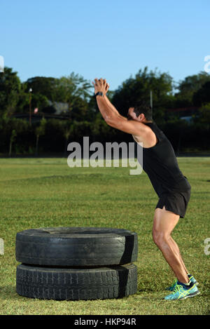 sport man start jumping on tire in green grass park Stock Photo