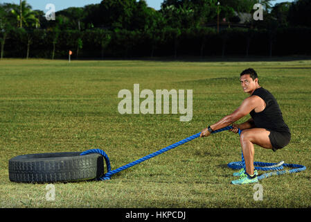 sport man workout with tire on green grass park Stock Photo