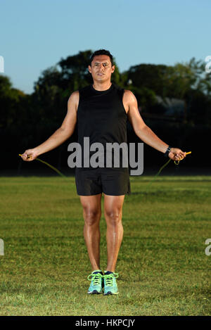 sportman man jumping rope on green lawn park Stock Photo