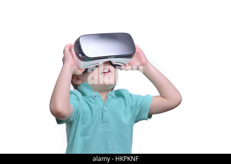 Amazed teen boy wearing virtual reality goggles watching movies or playing video games, isolated on white. Surprised teenager looking in VR glasses. Stock Photo