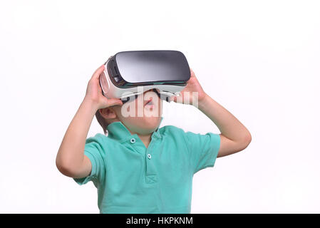 Amazed teen boy wearing virtual reality goggles watching movies or playing video games, isolated on white. Surprised teenager looking in VR glasses. Stock Photo