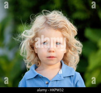 Beautiful boy three year old with long blond hair in the park Stock Photo