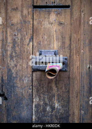 Junk advertising in the letterbox of an old door Stock Photo