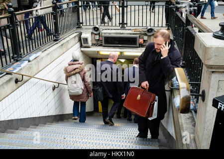 Man holding leather briefcase speaks on mobile phone at entrance to Oxford Circus underground station, London. UK Stock Photo