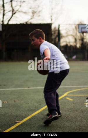 Child practicing playing basketball in a local park Stock Photo