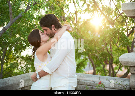 kissing married couple on balcony in sunset light Stock Photo