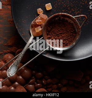 spoon with Turkish Delight and Cocoa powder in a sieve on a black plate, dark background Stock Photo