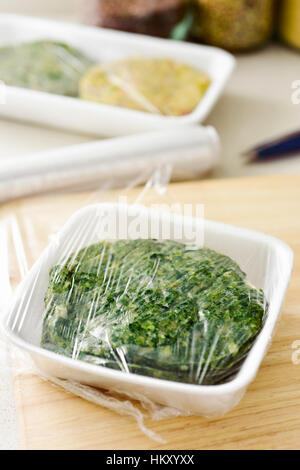 closeup of some different raw veggie burgers in plastic trays covered with plastic wrap ready to be introduced in the fridge or in the freezer Stock Photo