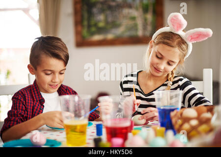 Elementary age kids painting eggs Stock Photo