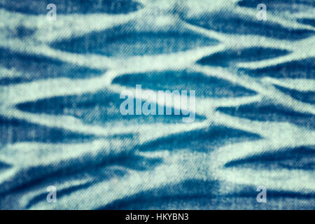 Color toned blurred close up picture of blue wrinkled jeans fabric, abstract background. Stock Photo