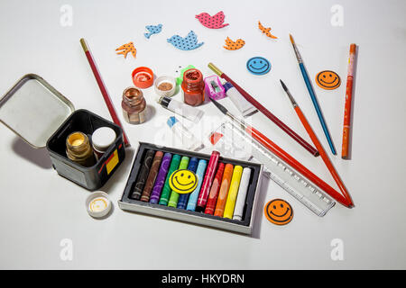 Kids tools and items for painting and creative works with color paints brushes plasticine pastels and pencils on white table top Stock Photo