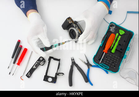 Repair of the modern  photo camera at professional service center. Hands of the master in special anti-electrostatic gloves. Top view studio shot Stock Photo