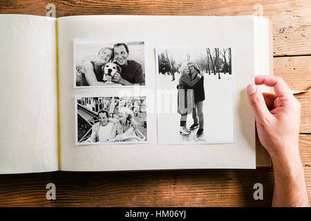 Hand holding photo album with pictures of senior couple. Studio Stock Photo