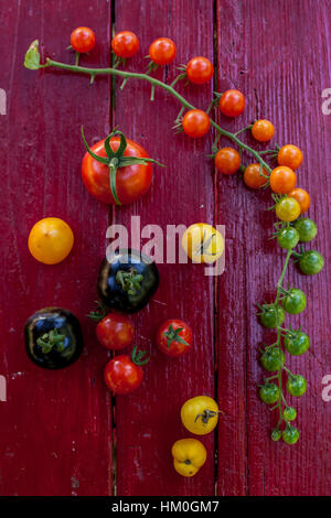 Variety of heirloom tomatoes in a rustic bowl and on a light wood surface Stock Photo