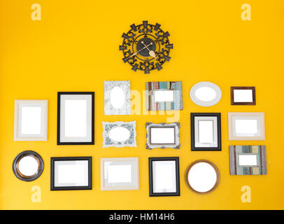 Several frames with vintage clock on the yellow wall Stock Photo