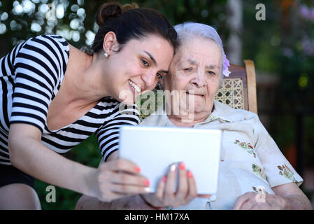 girl take selfie on tablet with old grandma Stock Photo