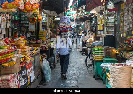 A man carrying a tower of fabrics through New Market (formerly known as Hogg Market) in Kolkata (Calcutta), West Bengal, India. Stock Photo