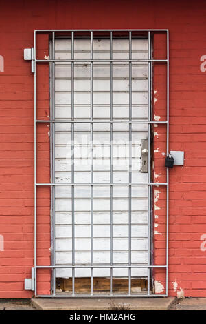 Red Wall with a Door secured by Iron Gratings Stock Photo