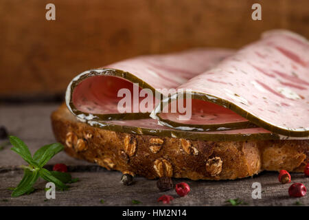 Open sandwich with specialty ham or salami made with pork meat and sheep cheese on wooden background Stock Photo
