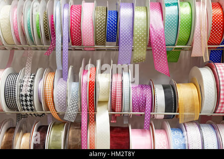 various colorful gift ribbon rolls on rack Stock Photo