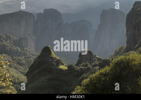 View over Roussanou Monastery, medieval 16th century nunnery, and the conglomerate pinnacles on a misty autumn evening;  Meteora, Greece, Stock Photo