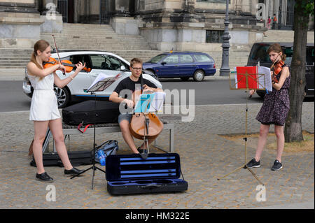 Two young female and one male teenagers playing classical music in front of Berlin Cathedral, Germany. Stock Photo