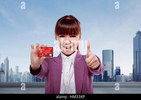 Young asian business woman showing credit card against cityscape background Stock Photo